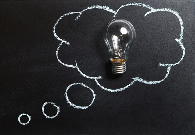 Lightbulb inside a thought cloud on blackboard