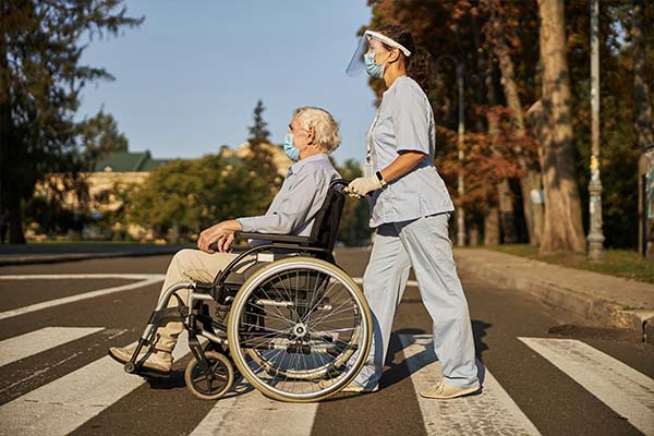 Care Worker Pushing Man In Wheelchair