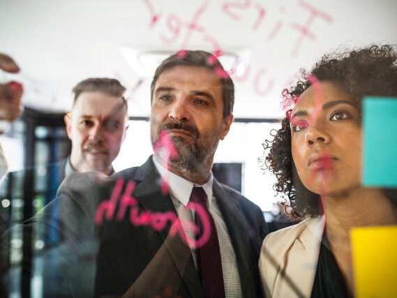 Three Colleagues Brainstorming On A Board