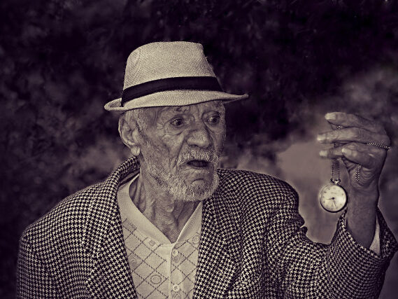 Hombre mayor sosteniendo un reloj de bolsillo