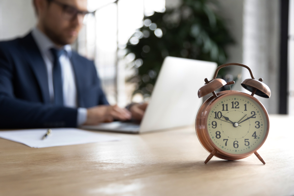 Businessman Working Next to Alarm Clock