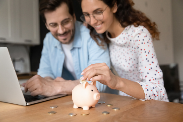 Couple Putting Money Into Piggybank