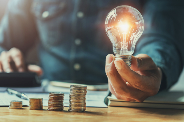 Man Holding Lightbulb Next To Coins