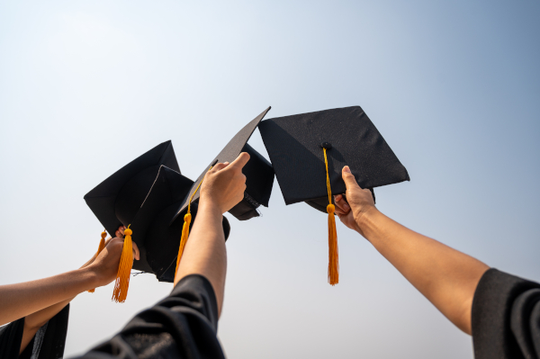 Three Graduates Holding Hats