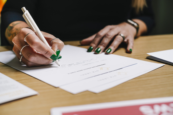 womans hands writing about naturalisation applications 2025