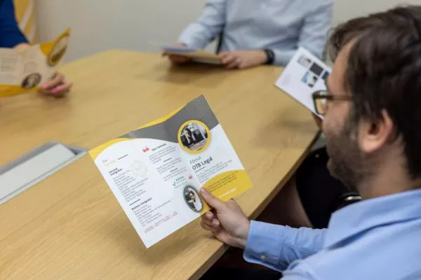Un avocat, assis à son bureau, lit une brochure sur le visa Global Talent et le congé s3C