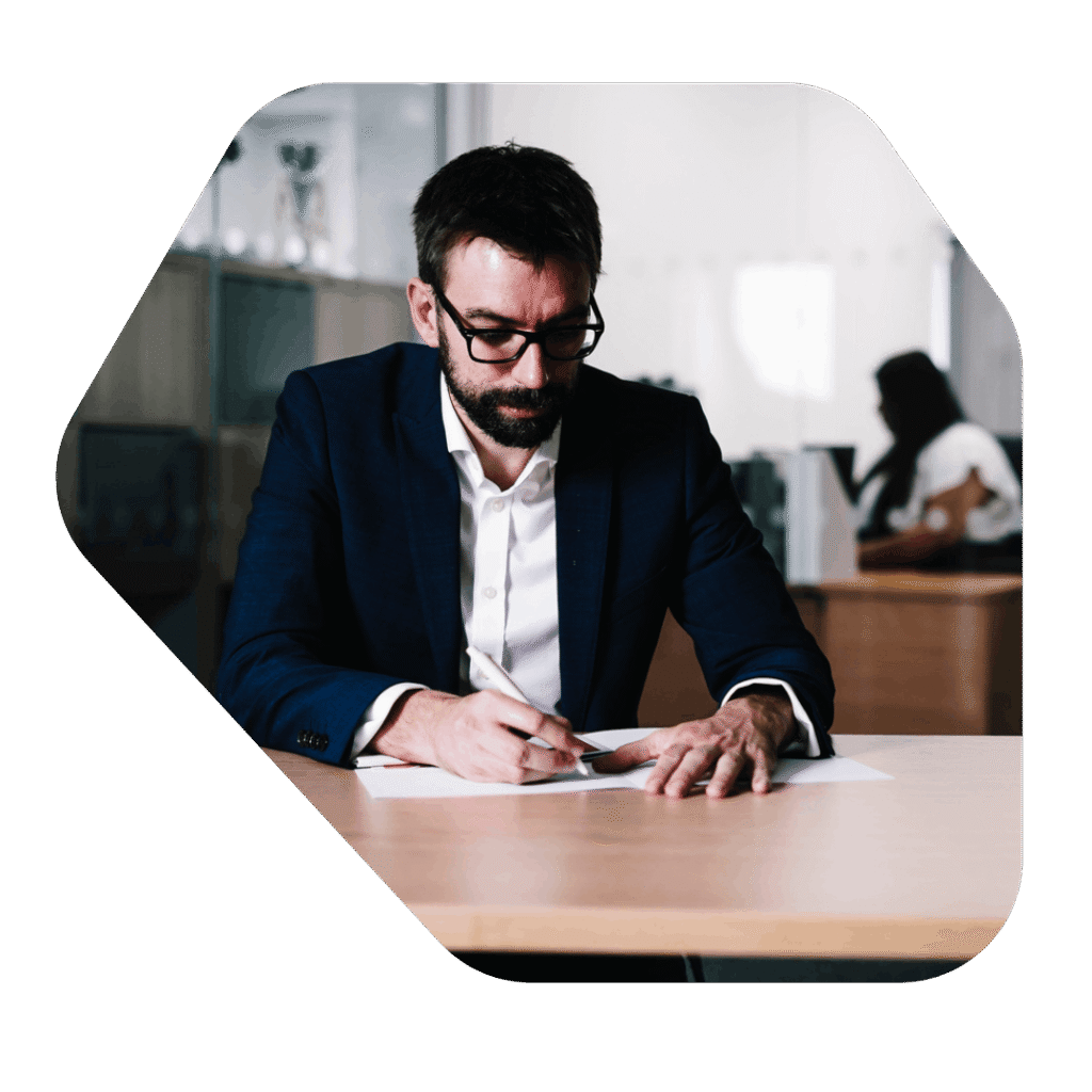 Male Director writing at desk. ILR 10 Year Long Residence Appointment