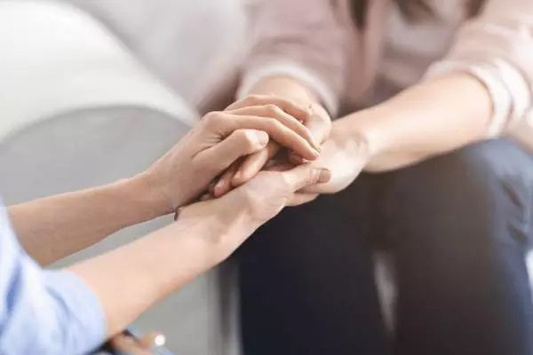 लोग एक-दूसरे का हाथ थामे हुए हैं। ब्रिटेन के घरेलू हिंसा आव्रजन नियम।