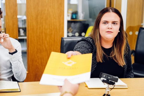 Une femme remet une brochure d'OTB Legal concernant l'audit de conformité des licences de parrainage du ministère de l'Intérieur en 2026